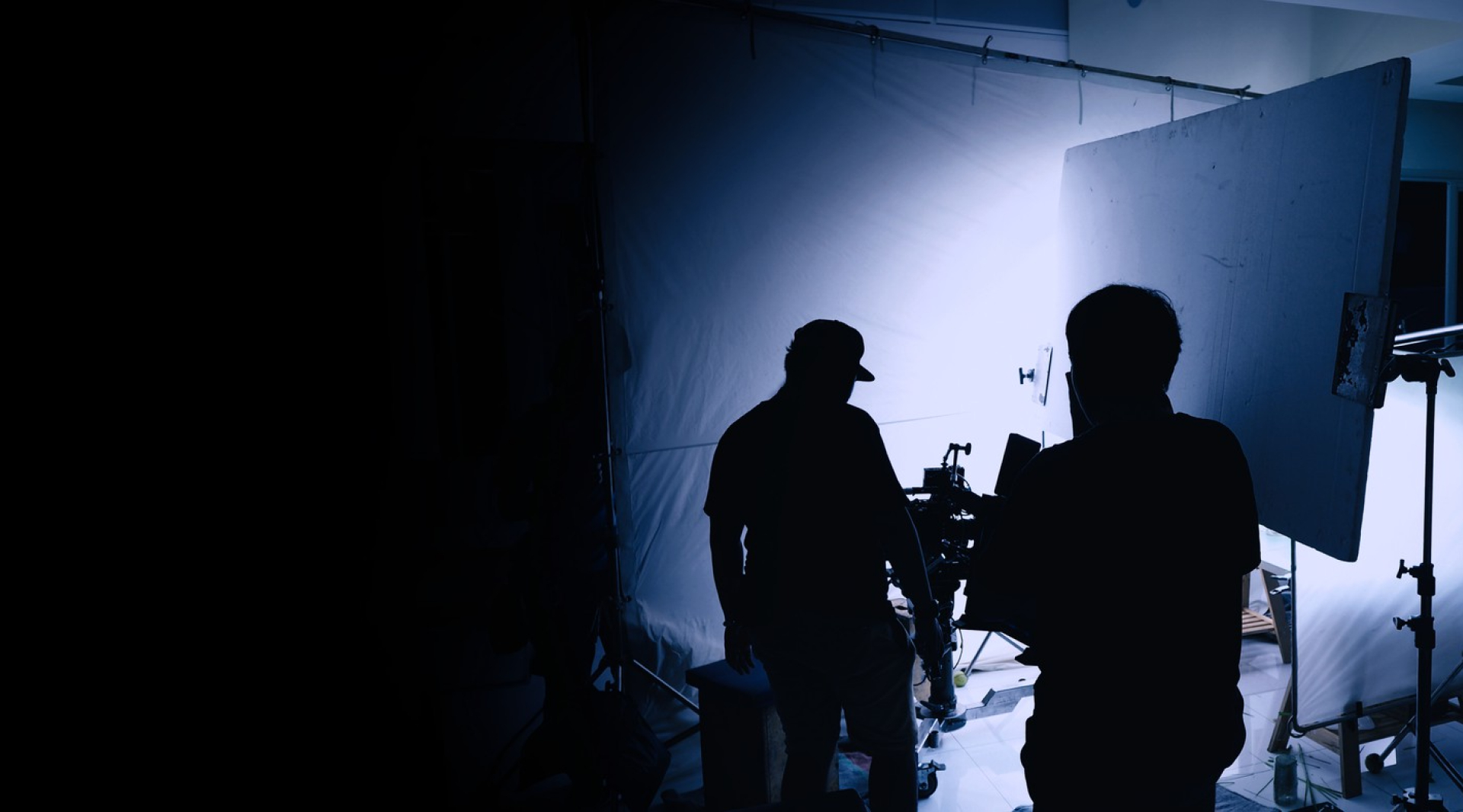 Two filmmakers working on a film set with bright studio lights behind them - Keep it Short